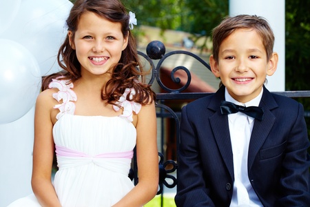 Portrait of boy groom and his cute bride sitting in parkの写真素材