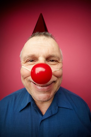 Portrait of a cheerful man with red nose smiling at camera on fools dayの写真素材