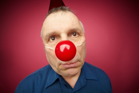 Portrait of unhappy man with a red nose celebrating all fools dayの写真素材