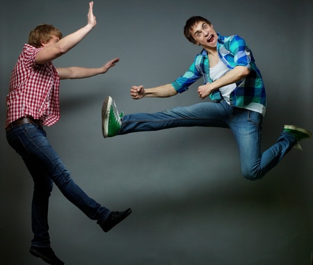 Guy jumping into air and kicking his friend, fools day seriesの写真素材