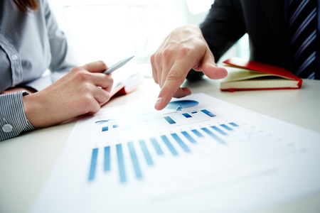 Image of male hand pointing at business document during discussion at meeting