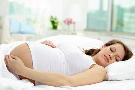 Photo of beautiful pregnant woman sleeping in bedの写真素材