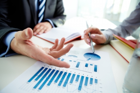 Image of male hand pointing at business document during discussion at meeting