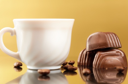 Photo of porcelain coffee cup with coffee beans and chocolates near byの写真素材