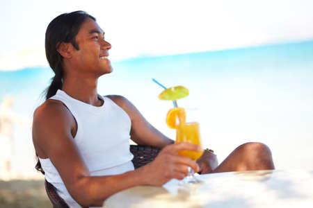 Young Latino man with cocktail during vacation on resortの写真素材