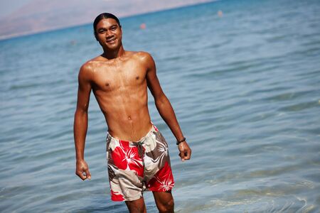 Young man looking at camera while standing in waterの写真素材