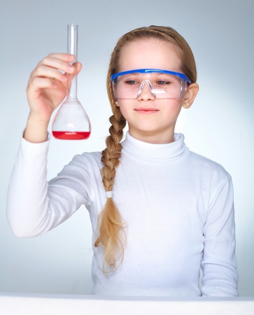 A little girl holding flask with red liquidの写真素材