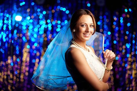 Joyful bride in an elegant dress and white veil posing in front of the cameraの写真素材