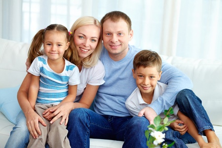 Portrait of happy family with two children sitting at home 
