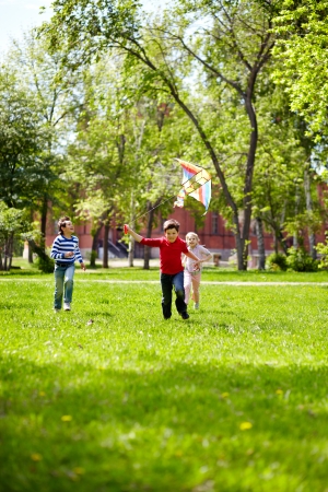 Image of joyful friends playing with kite outdoors の写真素材