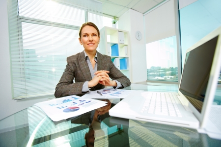Cheerful business lady smiling at camera at her workplaceの写真素材