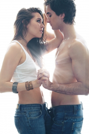 Young sensual lovers holding hands while the sun beaming between themの写真素材