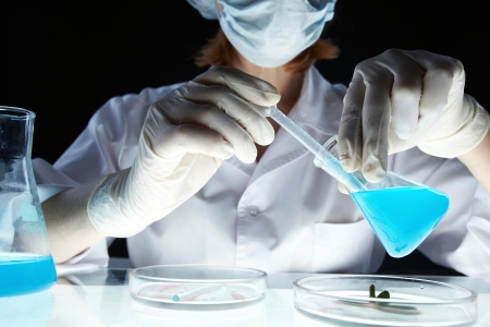 Lab worker withdrawing substance from beaker into pipetteの写真素材