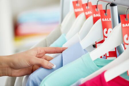 Photo of human hand searching through hangers with clothesの写真素材
