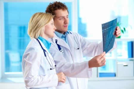 Portrait of young doctor commenting x-ray exam results to his colleagueの写真素材