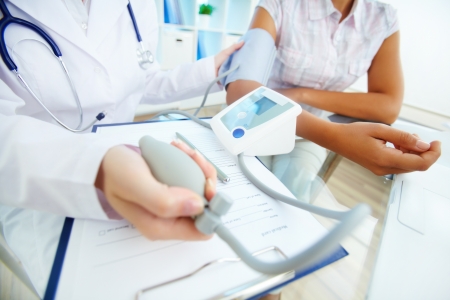 Close-up of tonometer by patients arm during blood pressure measuring at medical consultationの写真素材