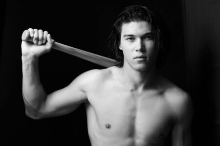 Close-up portrait of muscular man posing with a batの写真素材