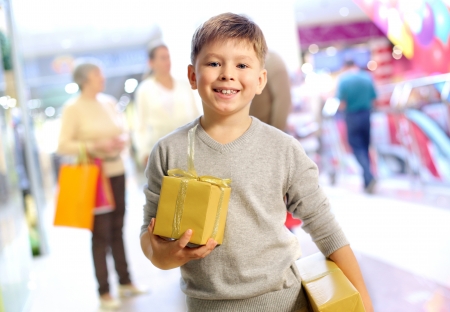 Portrait of happy child holding gift box with his family on backgroundの写真素材