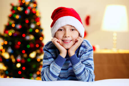 Adorable boy in Santa hat smiling and looking at cameraの写真素材