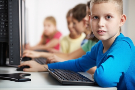 Portrait of smart lad looking at camera at computer lessonの写真素材
