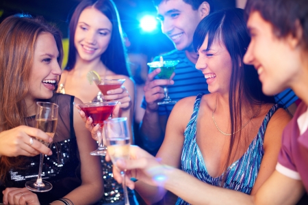 Portrait of joyful friends toasting at birthday party with focus on two laughing girlsの写真素材