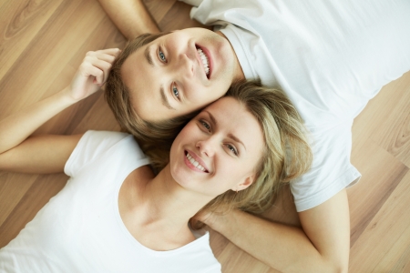 Above angle of young couple lying on the floor and looking at cameraの写真素材