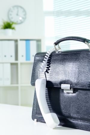 Image of black leather briefcase and white phone receiver in officeの写真素材