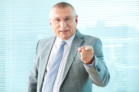 Portrait of elderly businessman pointing and looking at cameraの写真素材