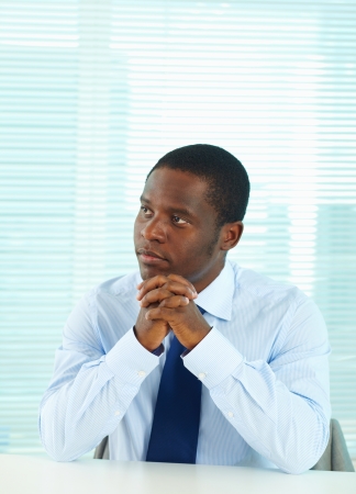 Portrait of pensive African businessman sitting in officeの写真素材