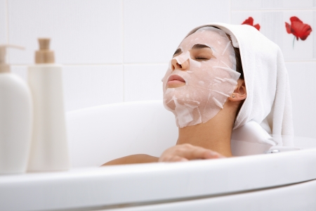 Image of serene woman with facial mask enjoying bath in spa salonの写真素材