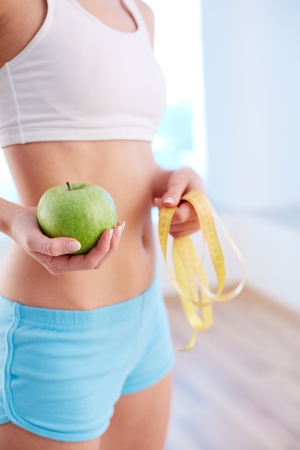 Vertical shot of a fit female holding a green appleの写真素材