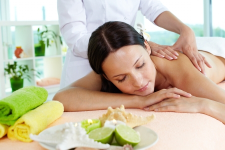 Photo of a girl lying on the massage table, massage therapist doing the procedureの写真素材