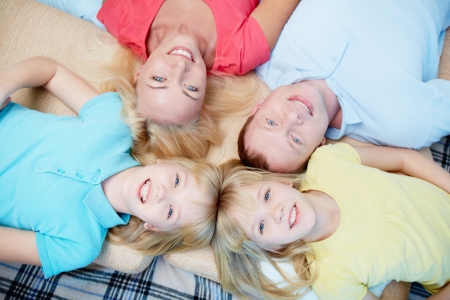 Above angle of happy family of four looking at camera at homeの写真素材