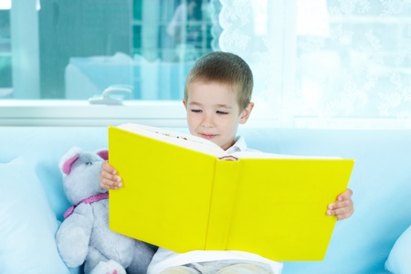 Boy reading interesting book at leisureの写真素材