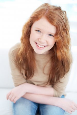 Teenage girl with wavy ginger hair looking at camera with smileの写真素材