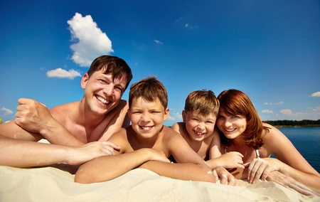  happy family lying on sand on summer vacationの写真素材