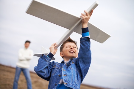 Photo of happy kid playing with toy airplane with his father on backgroundの写真素材
