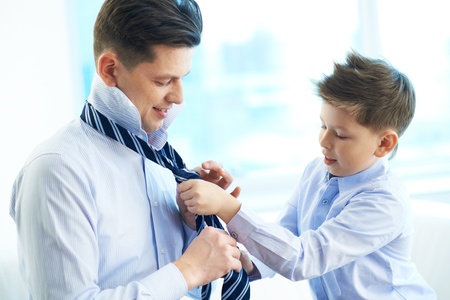 Photo of little boy helping his father tie necktieの写真素材