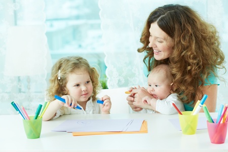 Beautiful mother and her children drawing at home の写真素材