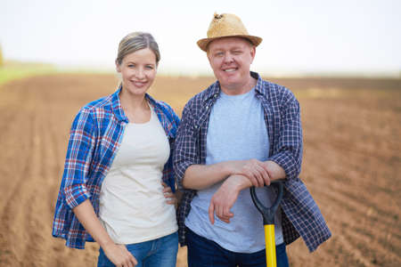 Image of two happy farmers on background of plowed fieldの写真素材