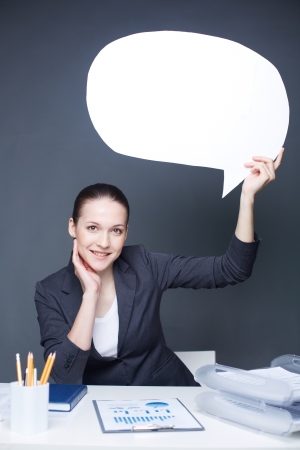 Portrait of young smiling female holding paper speech bubble and looking at cameraの写真素材