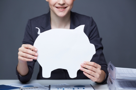 Close-up of young smiling female holding paper piggy bankの写真素材