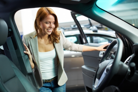 Photo of elegant woman choosing a new car in automobile centerの写真素材