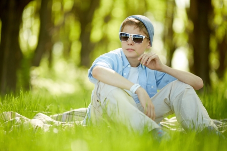 Portrait of cute lad in casual clothes and sunglasses having rest outside   の写真素材