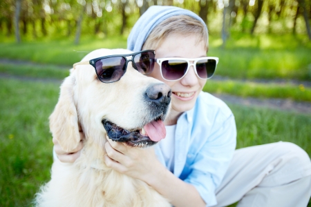 Portrait of cute lad and his fluffy friend in sunglasses outdoors   の写真素材