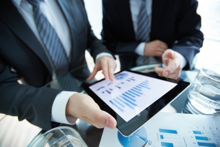 Close-up of business partners discussing document in touchpadの写真素材
