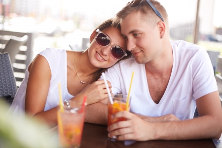 Young guy and his girlfriend sitting in cafe on summer dayの写真素材