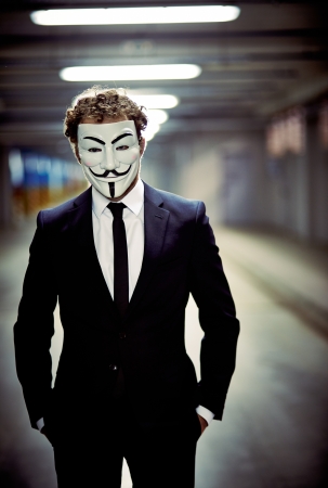 Foto de Vertical portrait of a business guy staring from behind anonymous mask - Imagen libre de derechos