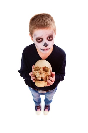 Photo of eerie boy with human skull looking at camera の写真素材