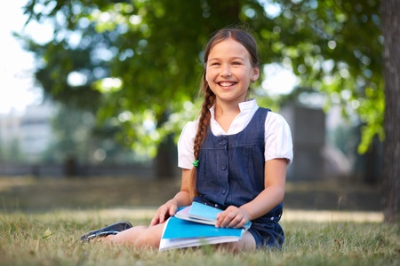 Image of cute schoolgirl with copybooks in summer park